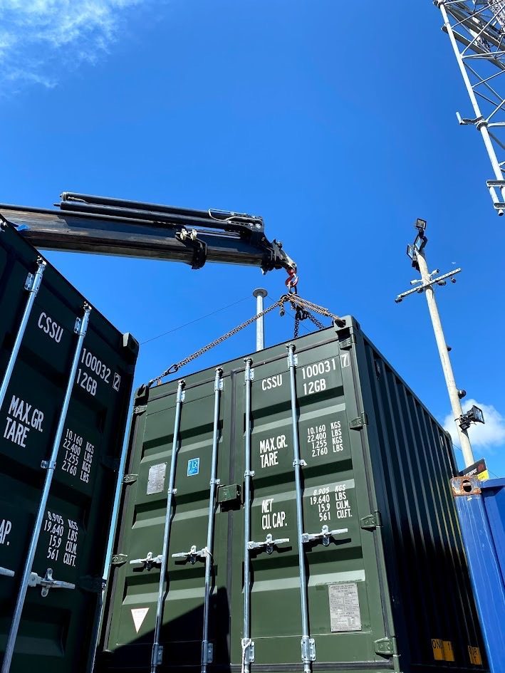crane lifting a shipping container by its corner mounting points