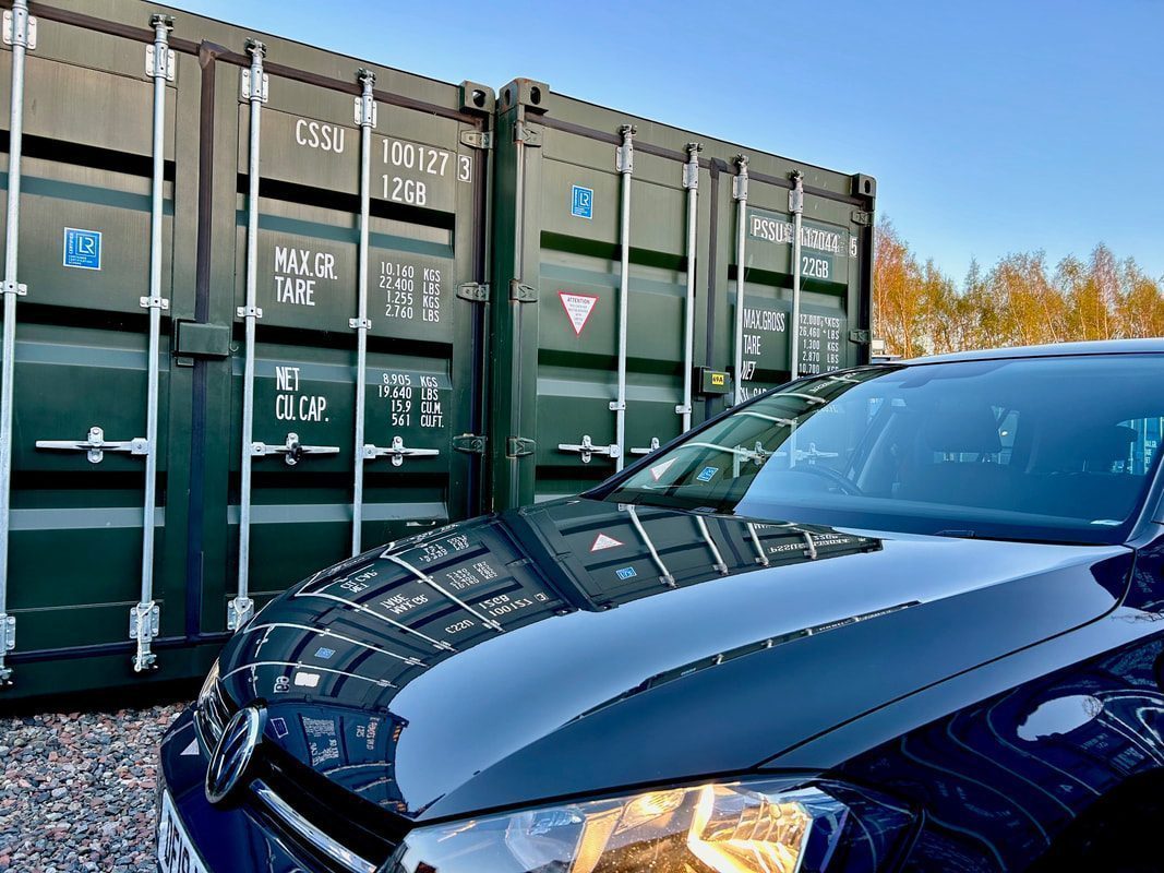 a 4x4 vehicle parked next to a row of green shipping containers promoting ground floor access to a storage unit