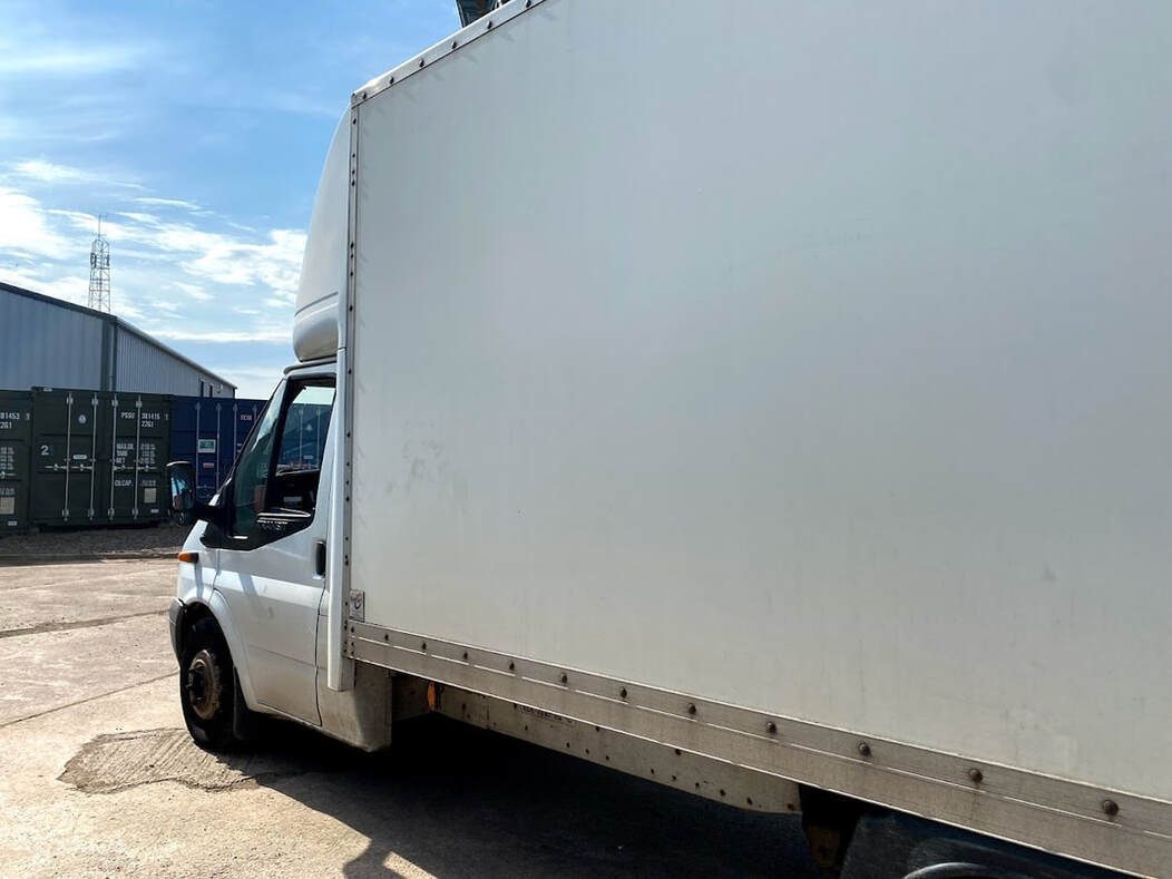 a rental van parked outside a shipping container storage unit with furniture being loaded into it