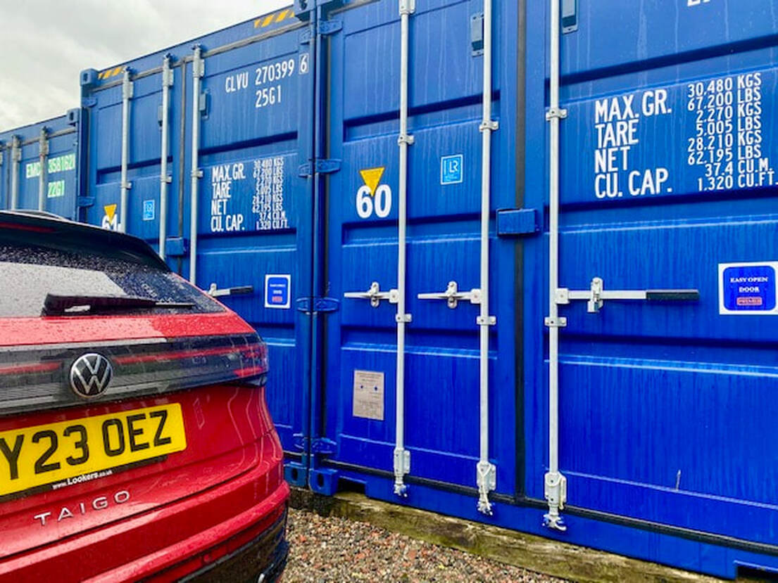 shipping storage container with car parked next to it