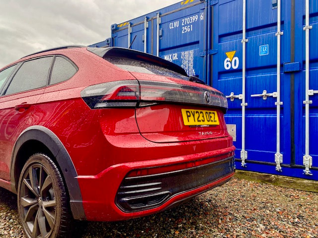 a car next to a shipping container