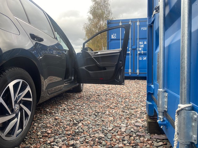 a car with its boot open about to unload from a storage container unit