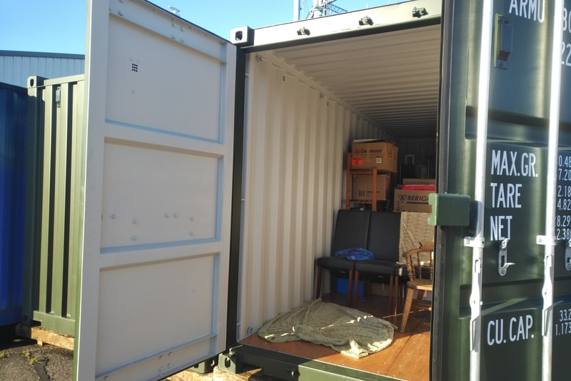 a shipping container with door open showing furniture inside