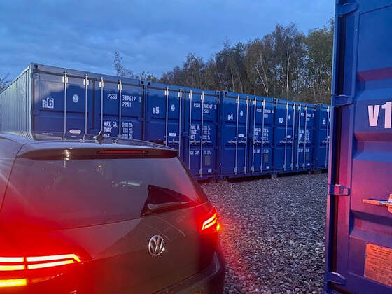 shipping container depot at night with a car parked beside a storage unit