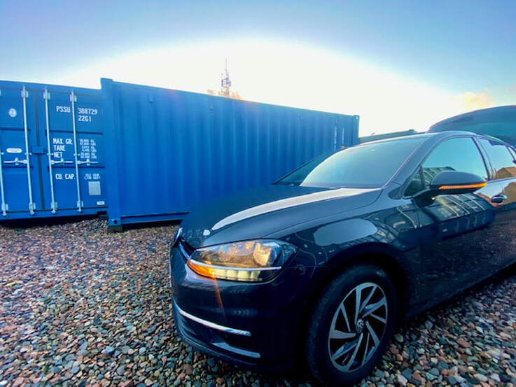 shipping container storage depot with a car in the foreground